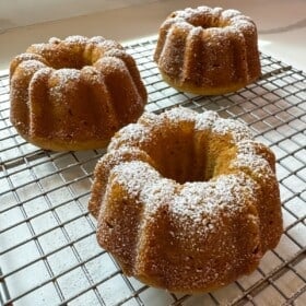 Mini pumpkin bundt cakes on a cooling rack dusted with powdered sugar.