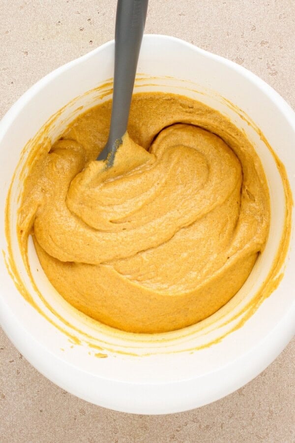 Pumpkin cake batter mixed in a white mixing bowl.