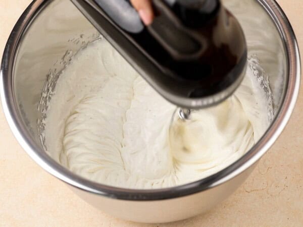 Whipped cream cheese frosting is being mixed in a stand mixer.