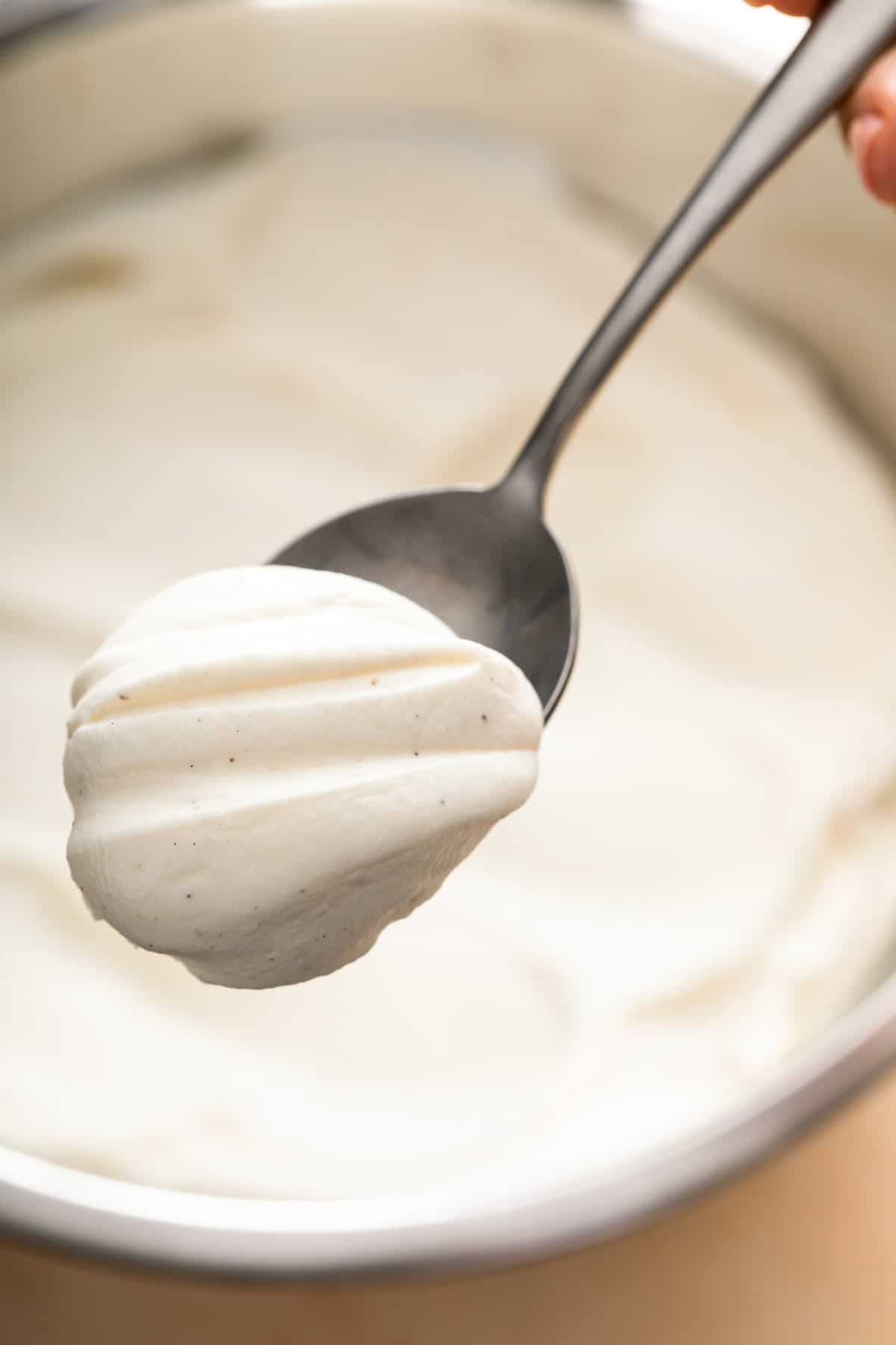 A close up image shows creamy white frosting on a spoon.