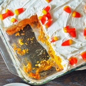 Candy corn cake in a baking dish topped with cream cheese whipped frosting.