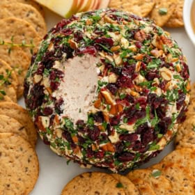 A single scoop has been removed from a cranberry cheese ball.