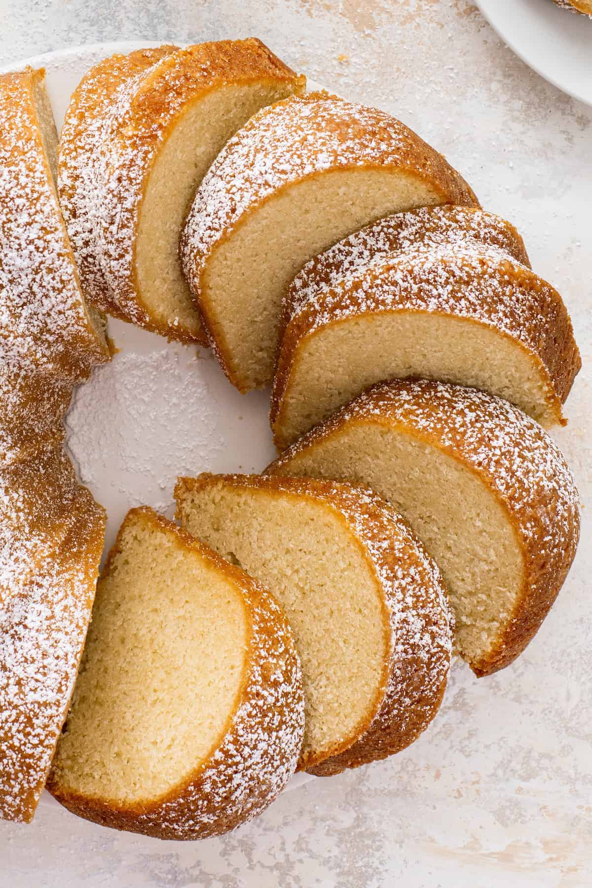 Moist buttermilk pound cake sliced into pieces leaning against each other on a a cake platter.