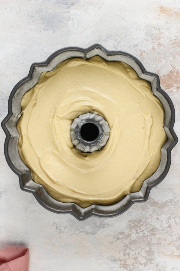 Unbaked cake batter added to a greased bundt pan.