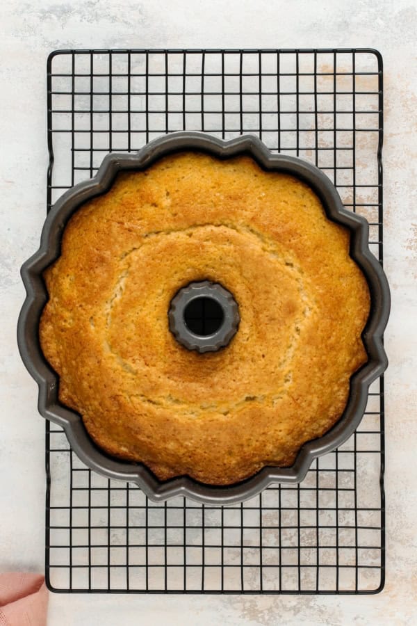 Baked cake in a bundt pan set on a cooling rack.