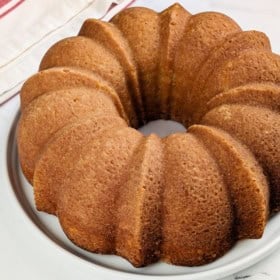 A whole traditional pound cake recipe made with buttermilk set on a white cake plate.