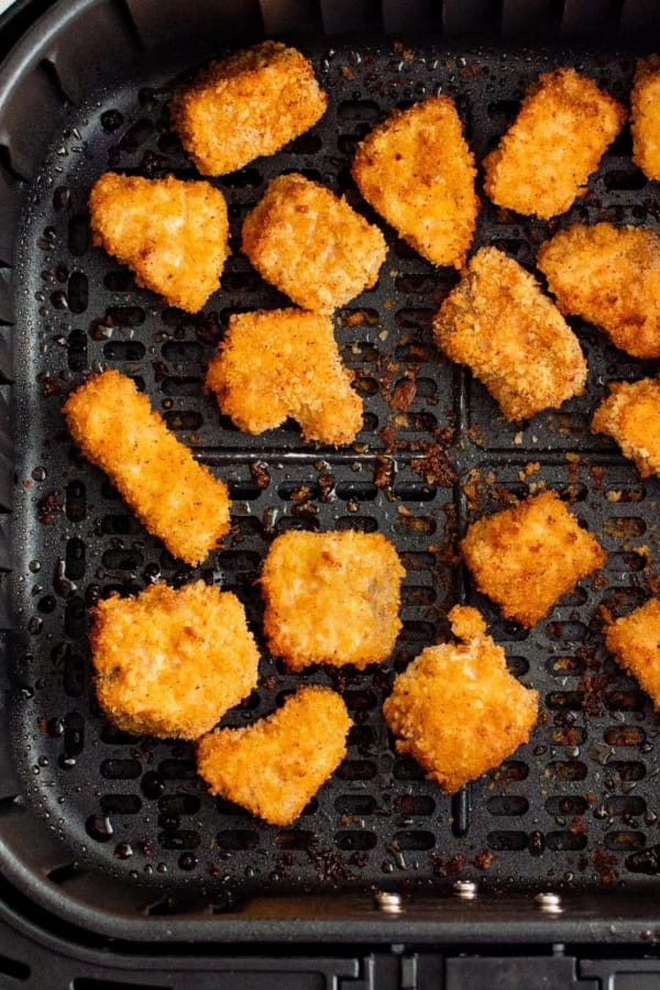 Salmon nuggets cooked to crispy golden brown perfection in the basket of an air fryer.