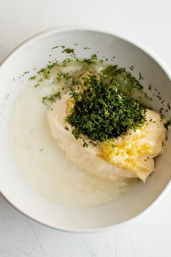 The ingredients for creamy dill dipping sauce are placed in a white bowl.