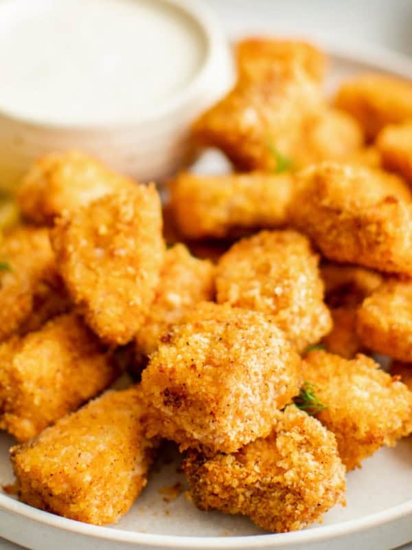 Crispy air fryer salmon bites are served with a small bowl of creamy dipping sauce.