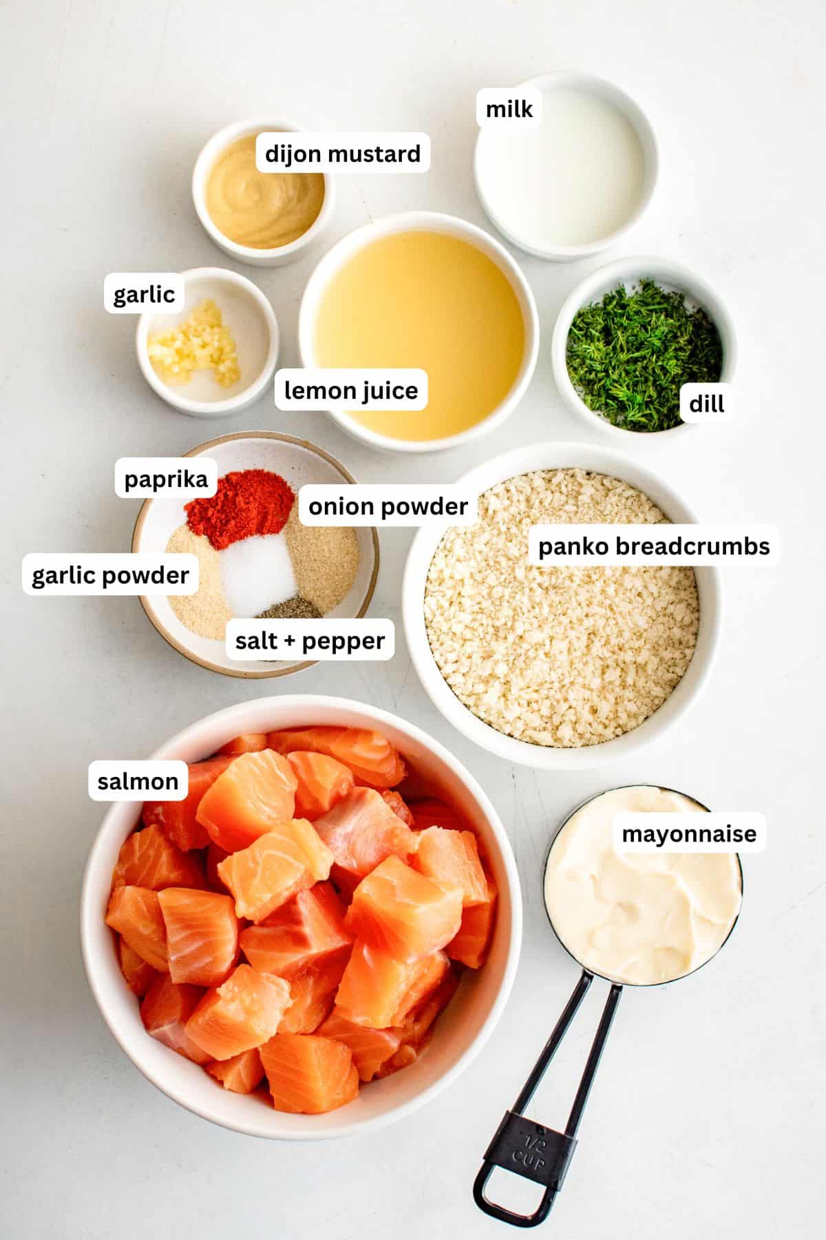 Ingredients for air fryer salmon bites recipe in order from top to bottom: Dijon Mustard, milk, garlic, lemon juice, dill, paprika, garlic powder, onion powder, salt, pepper, panko breadcrumbs, salmon and mayonnaise.