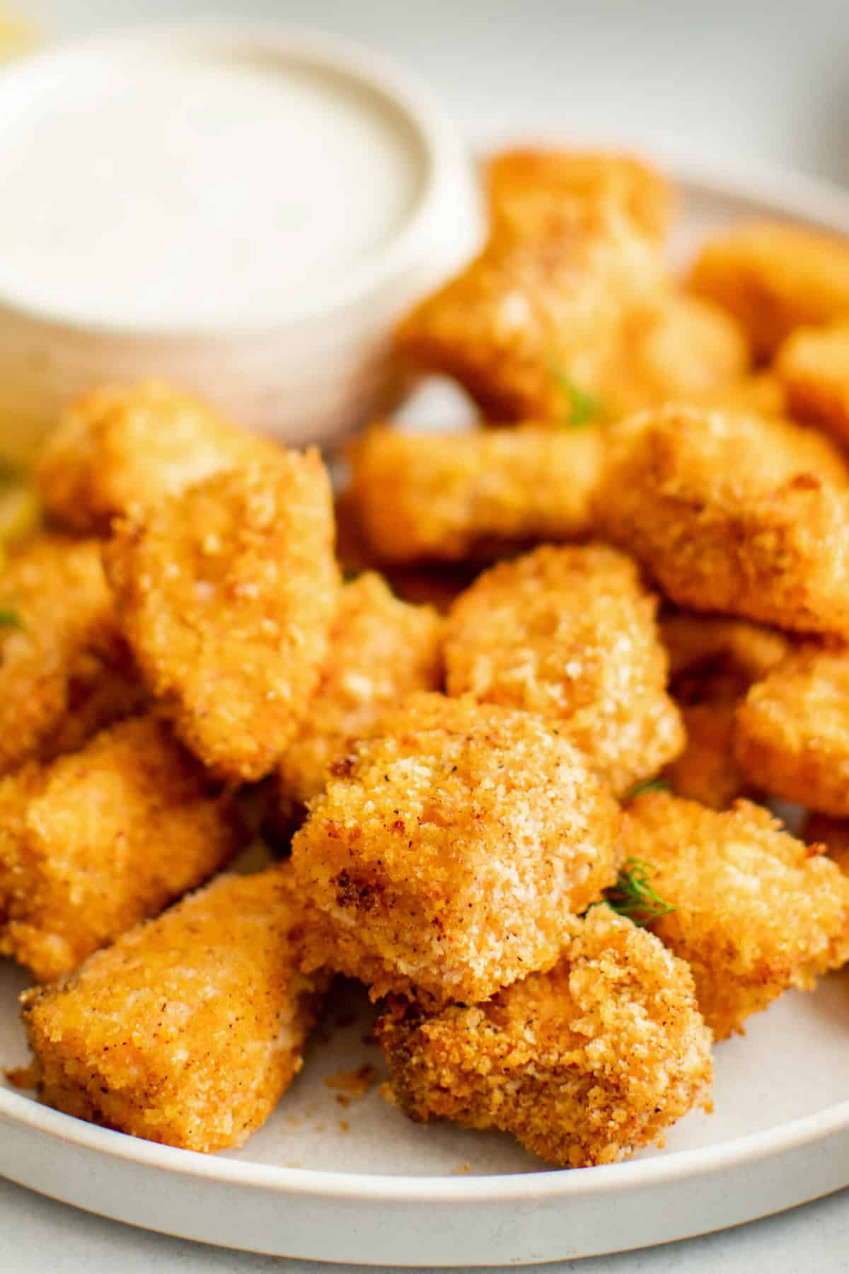 Crispy air fryer salmon bites are served with a small bowl of creamy dipping sauce.