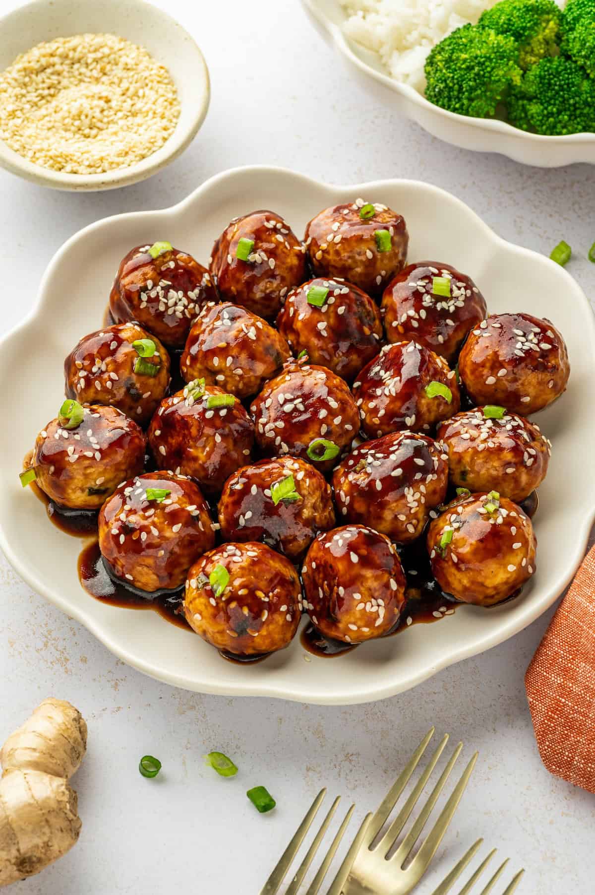 A large white serving platter topped with asian chicken meatballs.