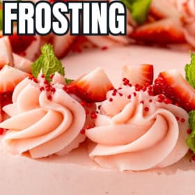 Strawberry buttercream frosting is piped into swirls on a layered cake.