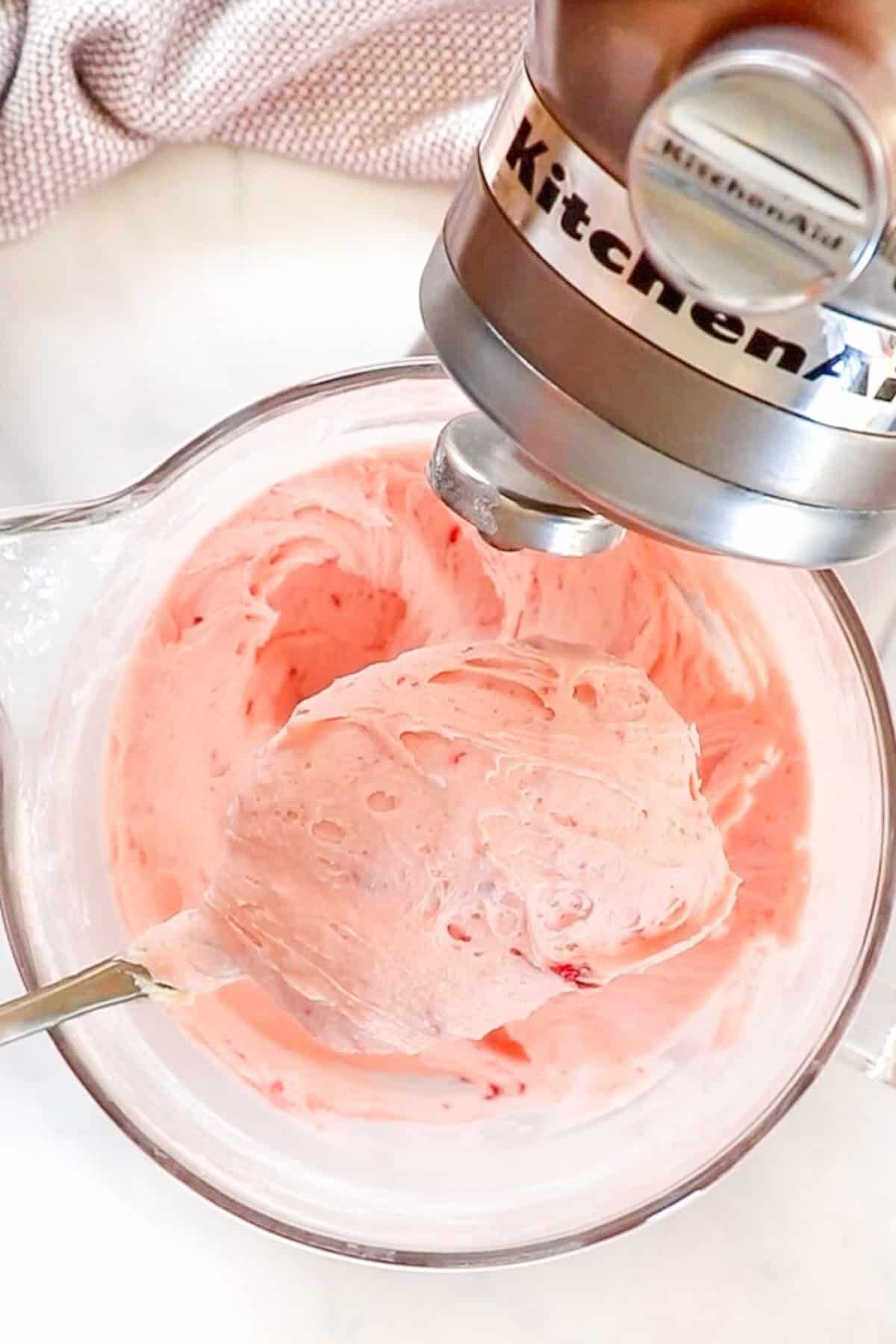 Strawberry buttercream is mixed in a stand mixer.