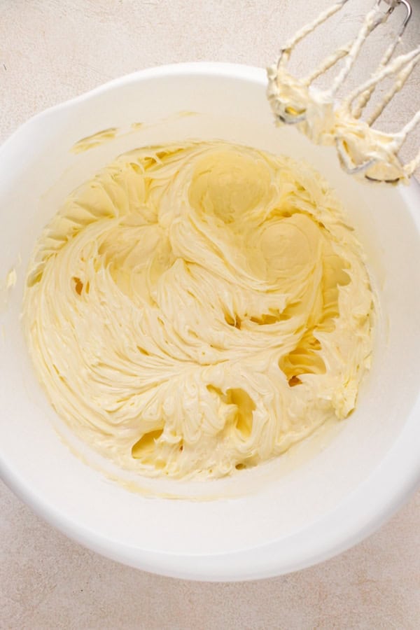 Butter is creamed in a large white bowl.