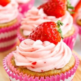 Strawberry cupcakes are topped with fresh berries.