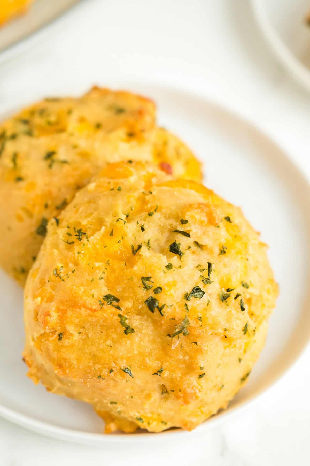 Two Red Lobster cheddar biscuits are placed on a small white plate.