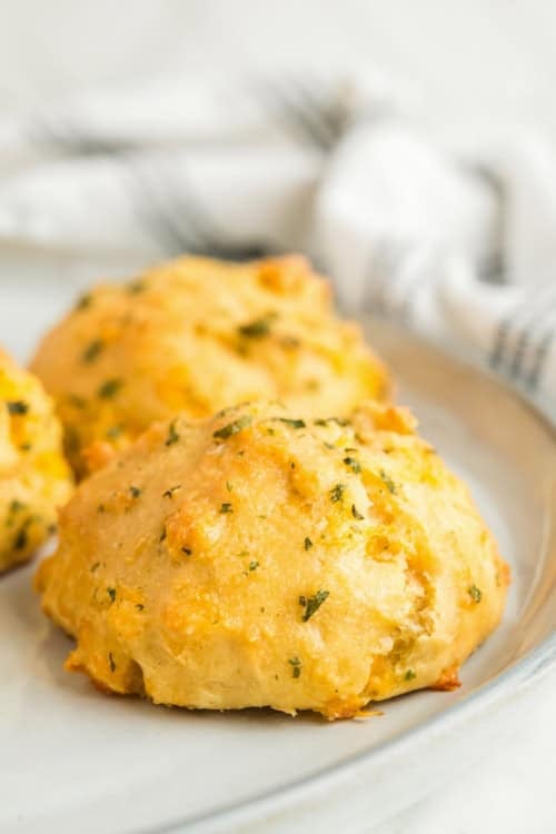 Soft, golden, buttery biscuits are on a round white plate.