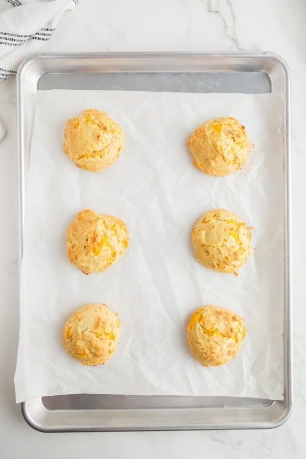 Baked cheddar biscuits on a prepared baking sheet.