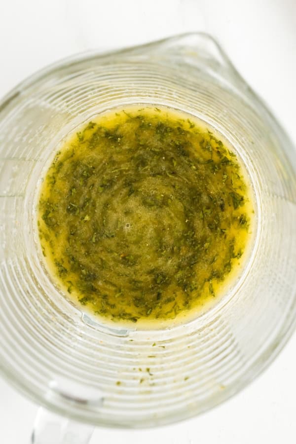 Melted butter, herbs, and seasonings are mixed together in a glass bowl.