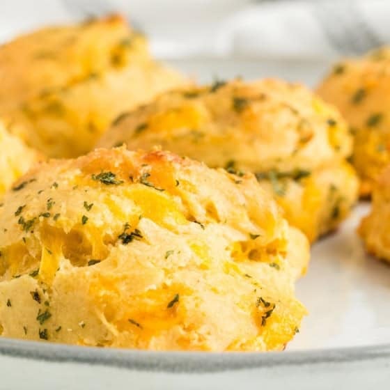 A batch of fresh baked cheddar bay biscuits are on a plate.