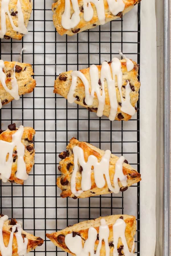 Baked scones on a wire cooling rack are drizzled with icing.