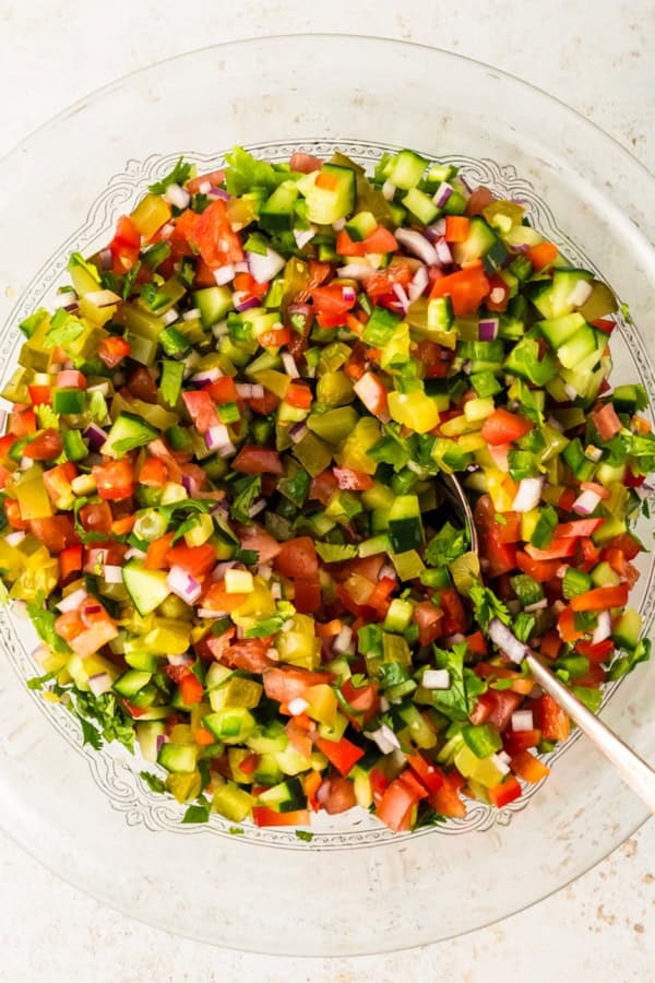 Calling all pickle lovers! This tangy Pickle de Gallo recipe is a game-changing condiment that adds a fresh, tangy twist to any meal. Pickle de Gallo is mixed in a large bowl with a serving spoon.
