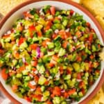 A large serving bowl is filled with fresh pickle salsa.