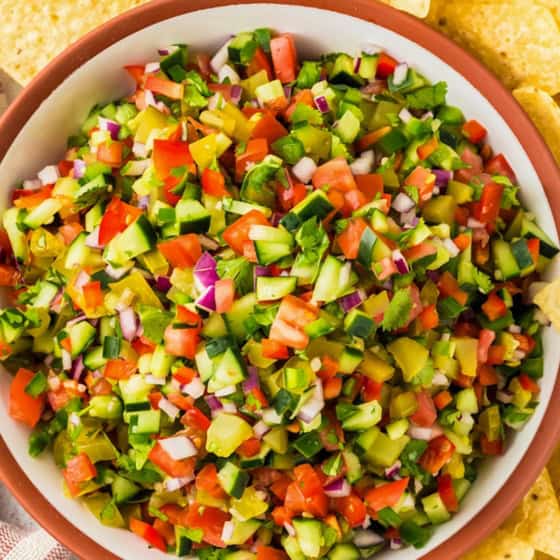 A large serving bowl is filled with fresh pickle salsa.