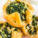 Three spinach puffs placed on a white serving plate.