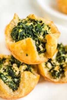 Three spinach puffs placed on a white serving plate.