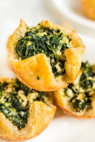 Three spinach puffs placed on a white serving plate.