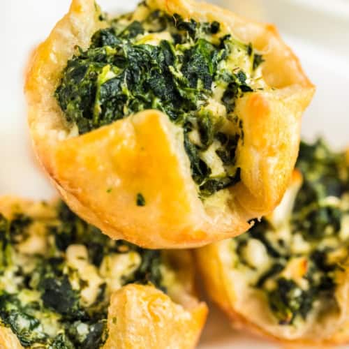 Three spinach puffs placed on a white serving plate.