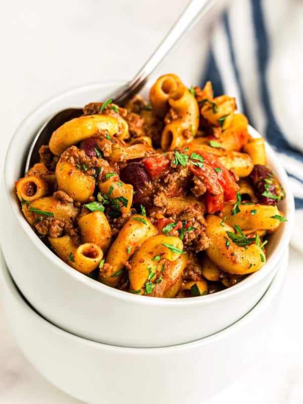 A white bowl is filled with cheesy goulash.