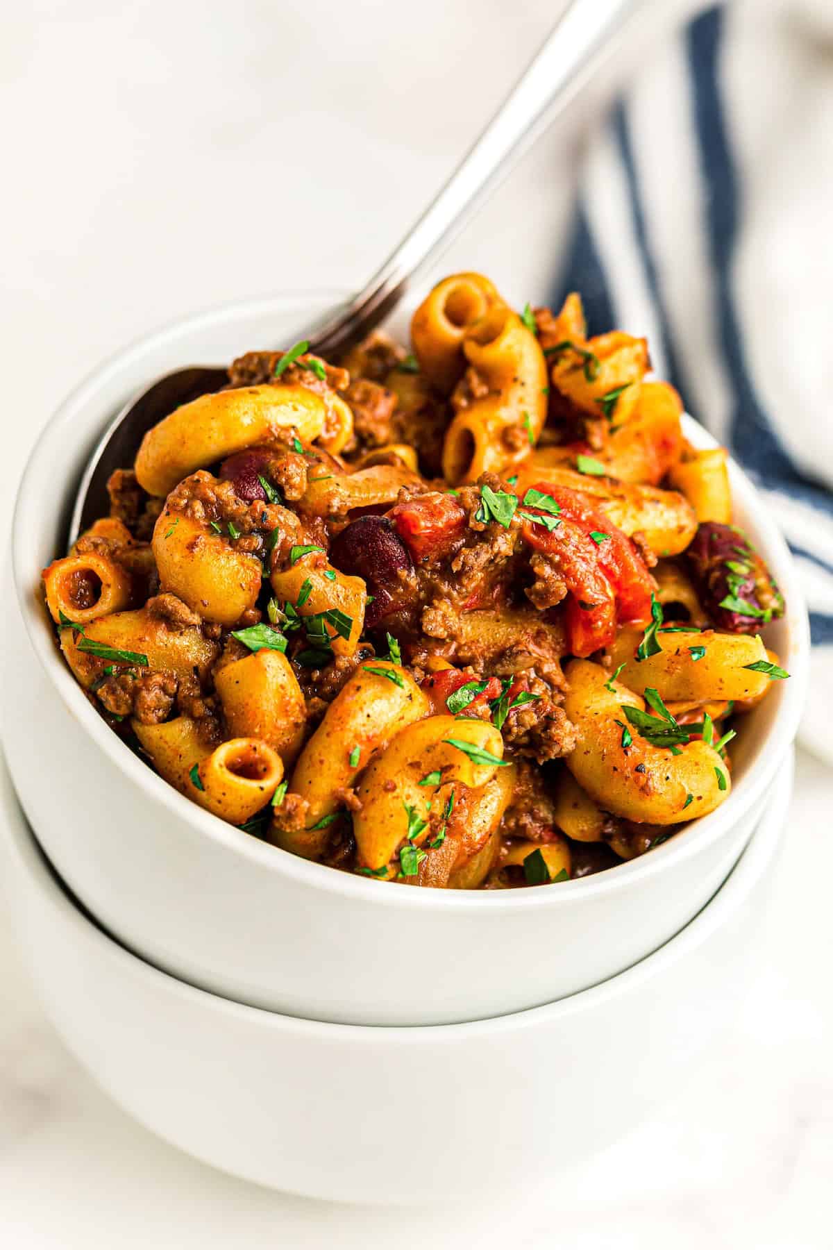A white bowl is filled with cheesy American goulash.
