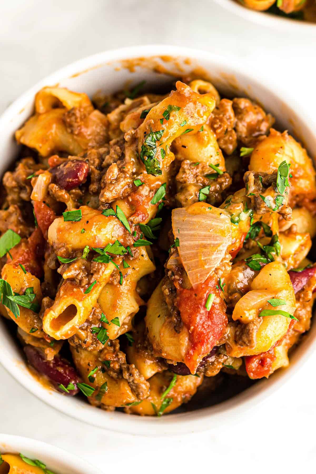 A single serving of American goulash is served in a white bowl.