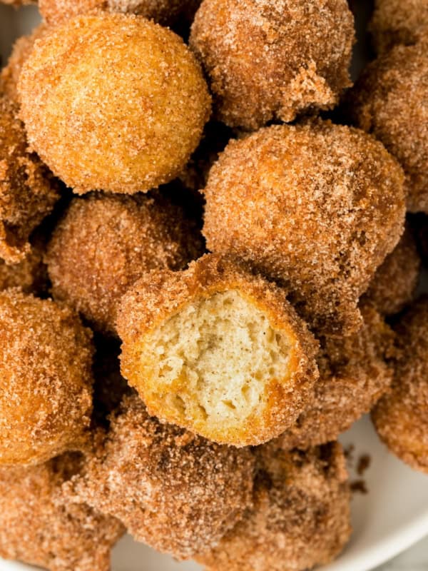 A single donut hole has been bitten into and placed back in the pile.