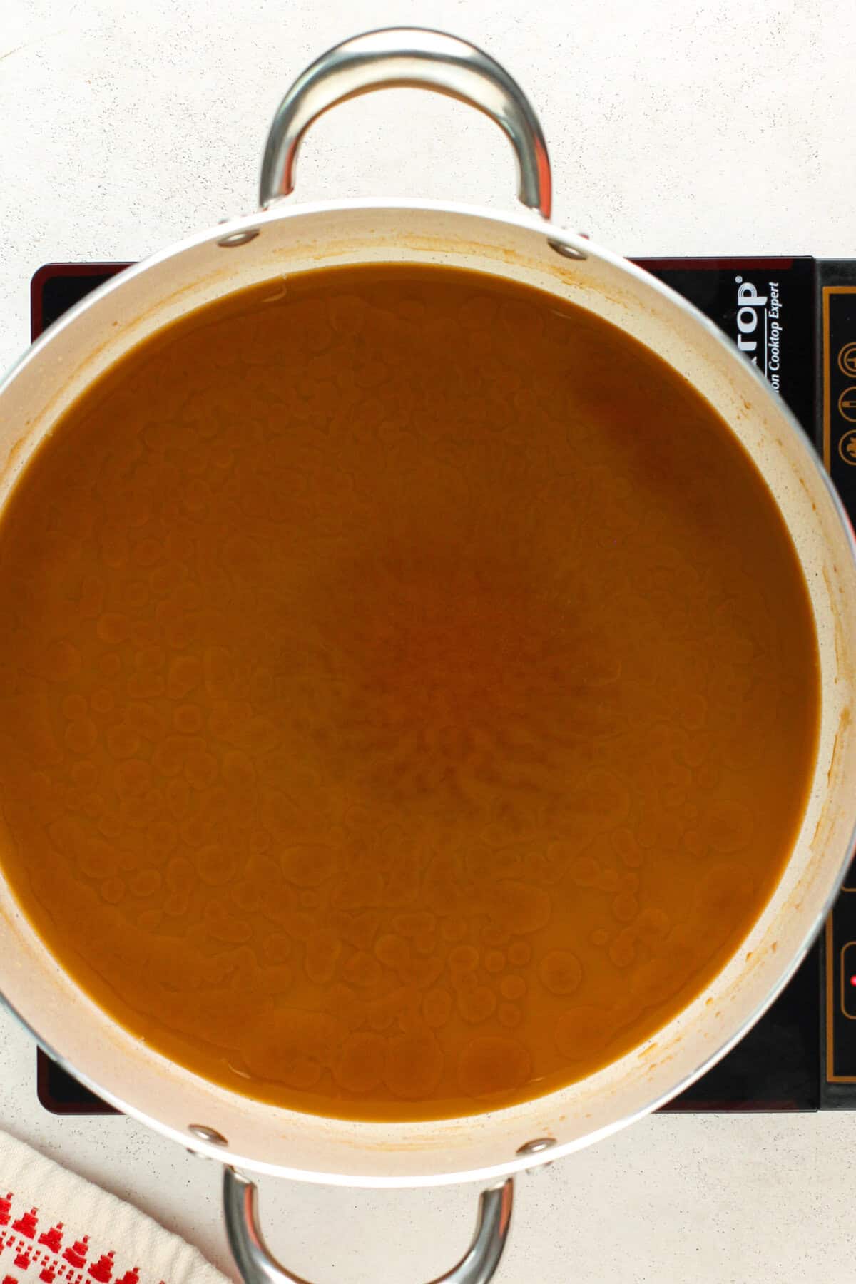 Dark brown roux is cooking in a large heavy bottomed pot.