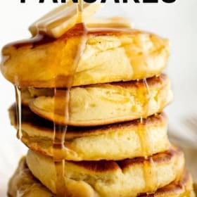 A stack of fluffy Japanese pancakes topped with melting butter and drizzled with syrup.