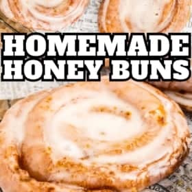 Glazed homemade honey buns arranged on parchment paper. The buns are golden brown and swirled with icing.