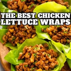 Close-up of lettuce wraps filled with seasoned ground chicken and chopped nuts, arranged on a wooden board.