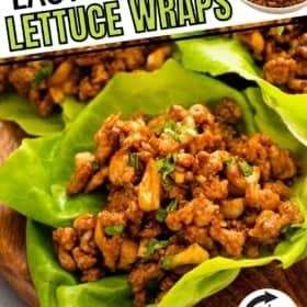 Close-up of three lettuce wraps filled with seasoned ground chicken on a wooden plate. A small bowl of chicken filling mixture is visible in the corner.