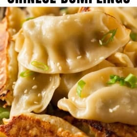 Close-up of golden-brown pan-fried Chinese dumplings garnished with sliced green onions and sesame seeds.