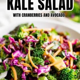 A bowl of colorful broccoli kale salad with cranberries, avocado, shredded carrots, and purple cabbage.
