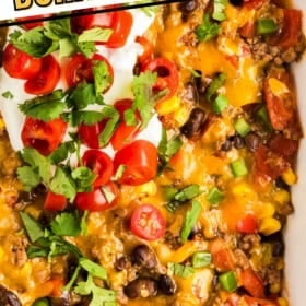 A Dorito casserole topped with melted cheese, ground beef, black beans, corn, diced tomatoes, jalapeños, and fresh cilantro.