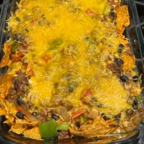 A taco casserole with Doritos baked with cheddar cheese on top.
