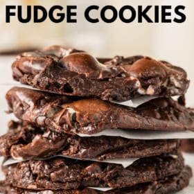 A stack of thick, rich chocolate fudge cookies is shown, with gooey chocolate pieces visible inside. The marshmallow chocolate cookies are placed on a cooling rack.