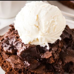 A serving of rich, gooey chocolate pudding cake topped with a large scoop of vanilla ice cream on a plate.