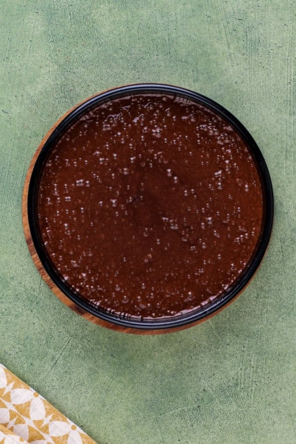 Rich, dark, and unbelievably moist, this Guinness Chocolate Cake is frosted with a sweet Bailey's buttercream. Perfect for St. Patrick's Day! A round cake pan is filled with chocolate Guinness cake batter, ready to be baked.