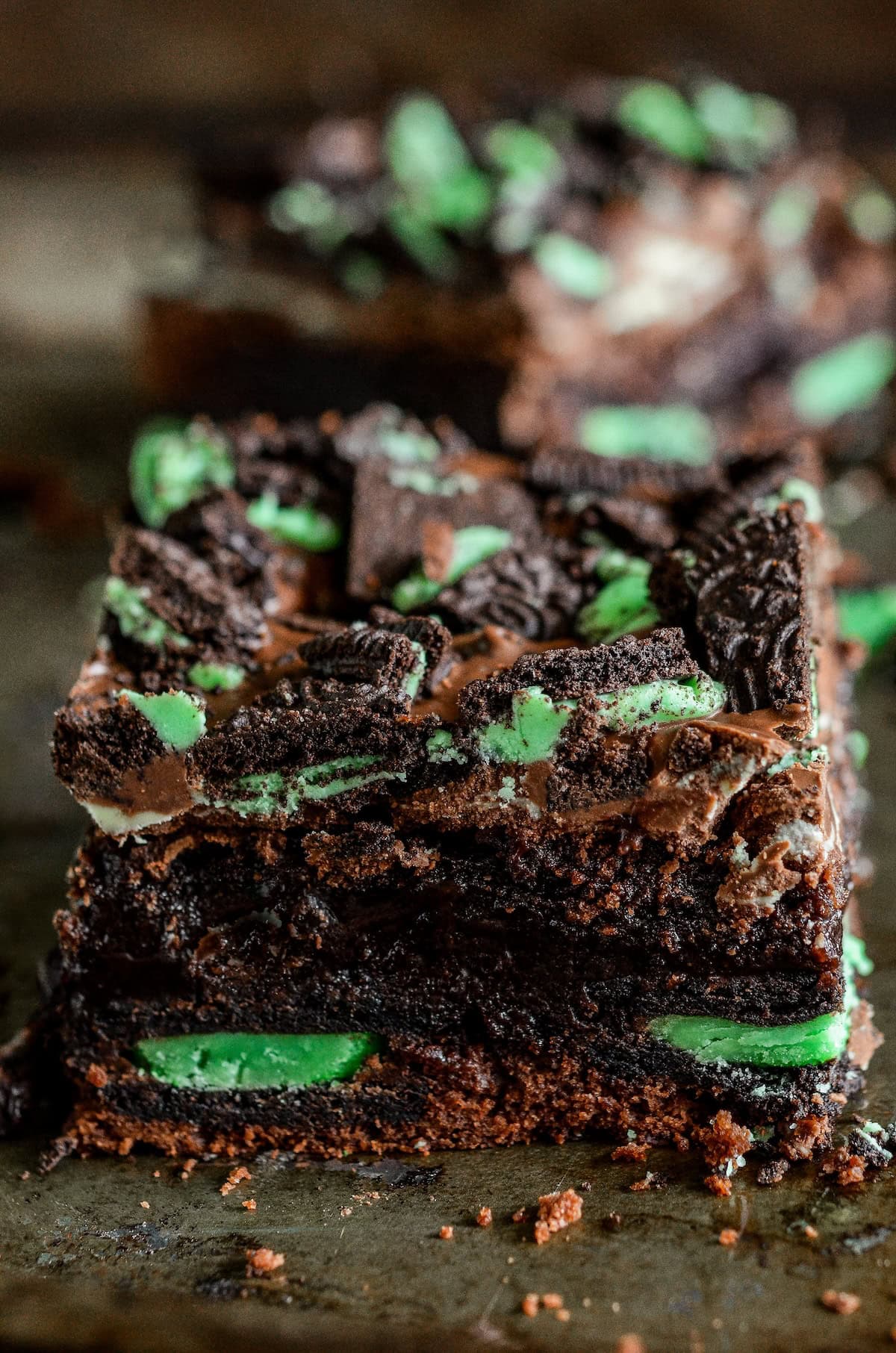 Fudgy chocolate brownies are filled with layers of Mint Oreos and Andes Mints to create these epic Andes Mint Brownies. Close-up of chocolate mint brownies showing a rich, fudgy texture with Mint Oreo cookies layered inside topped with melted andes mints and more chopped mint Oreo cookies.